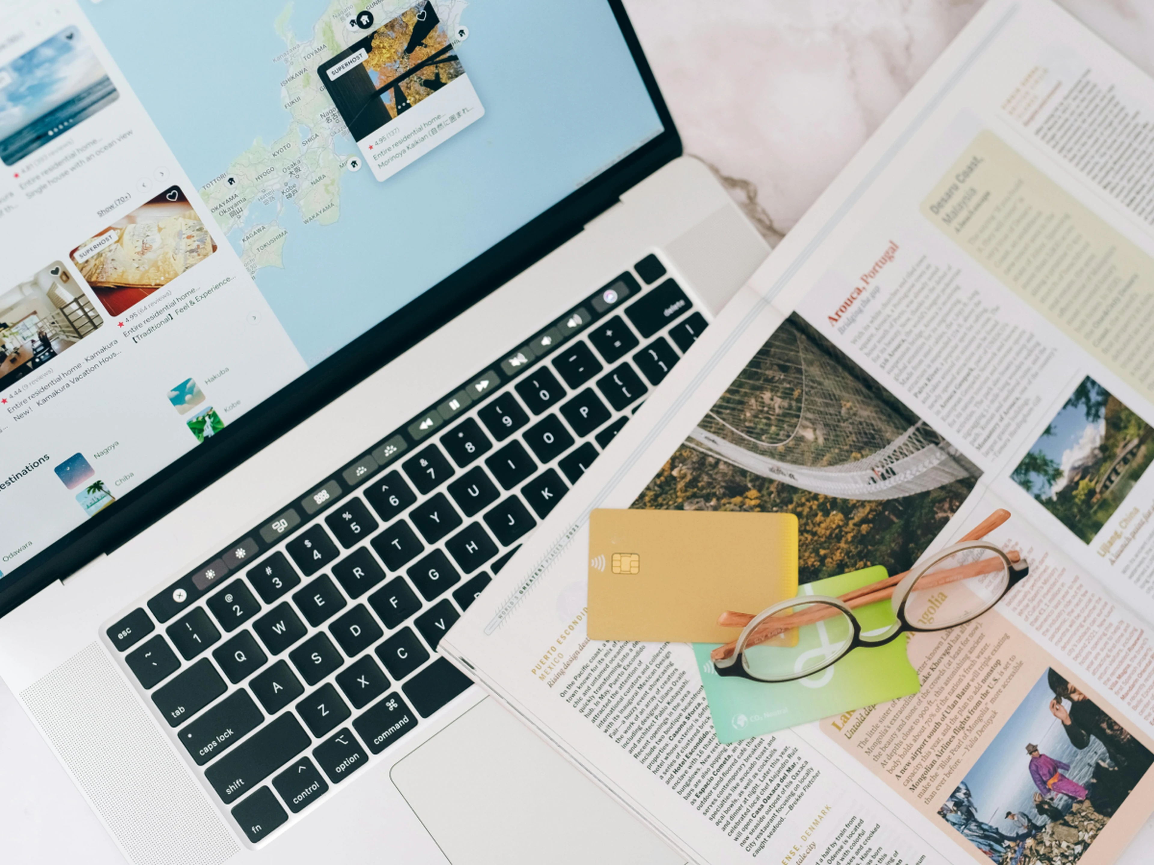 travel guide, credit cards and laptop displaying an accommodation search map