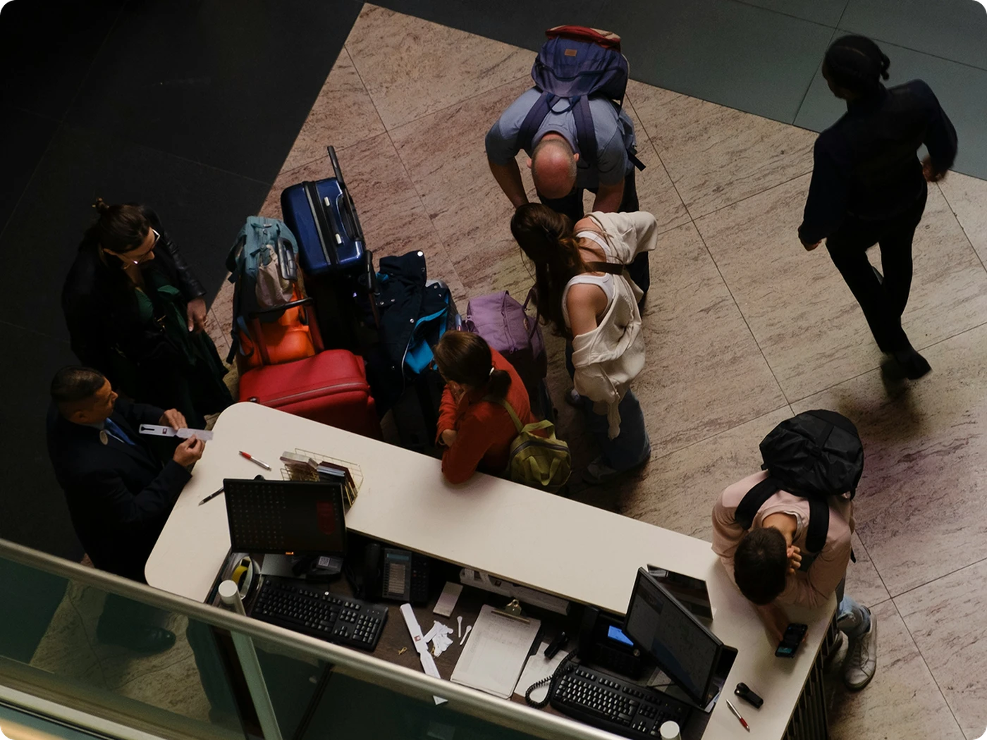 Lots of hotel guests waiting at the front desk of a hotel