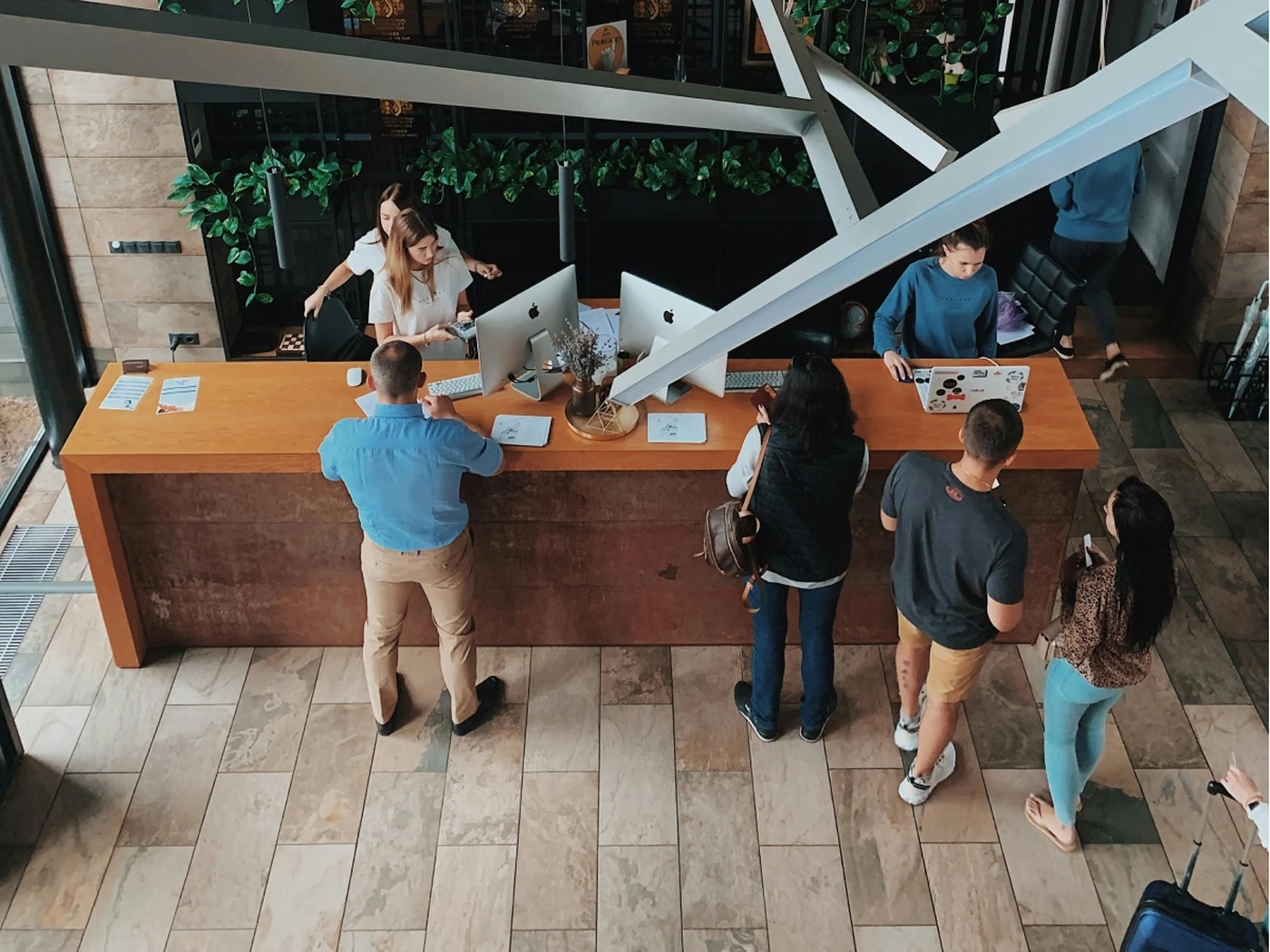 busy hotel reception with staff processing payments and multiple guests waiting