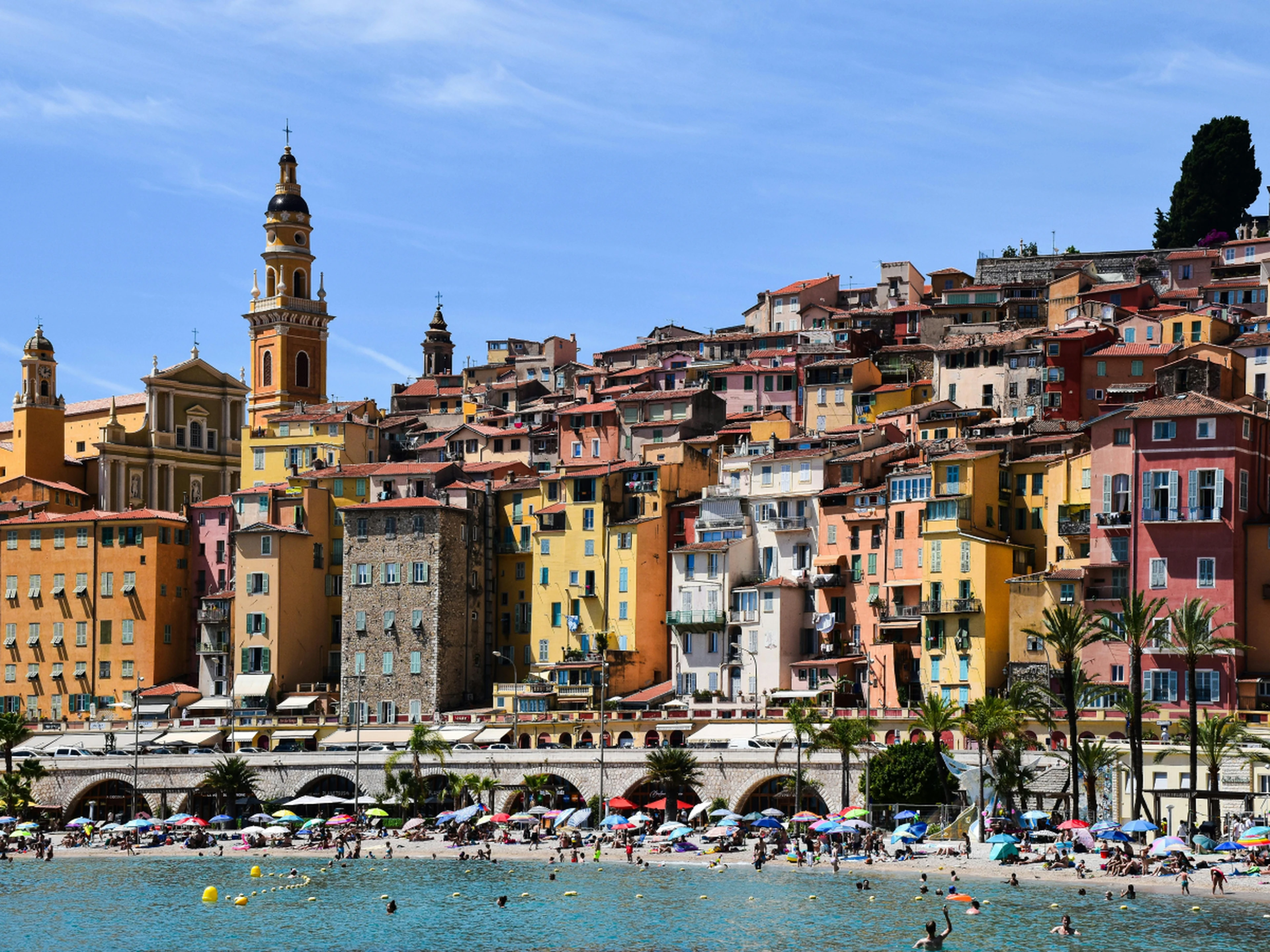 Colorful buildings along the côte d'Azur, France, with a crowded beach