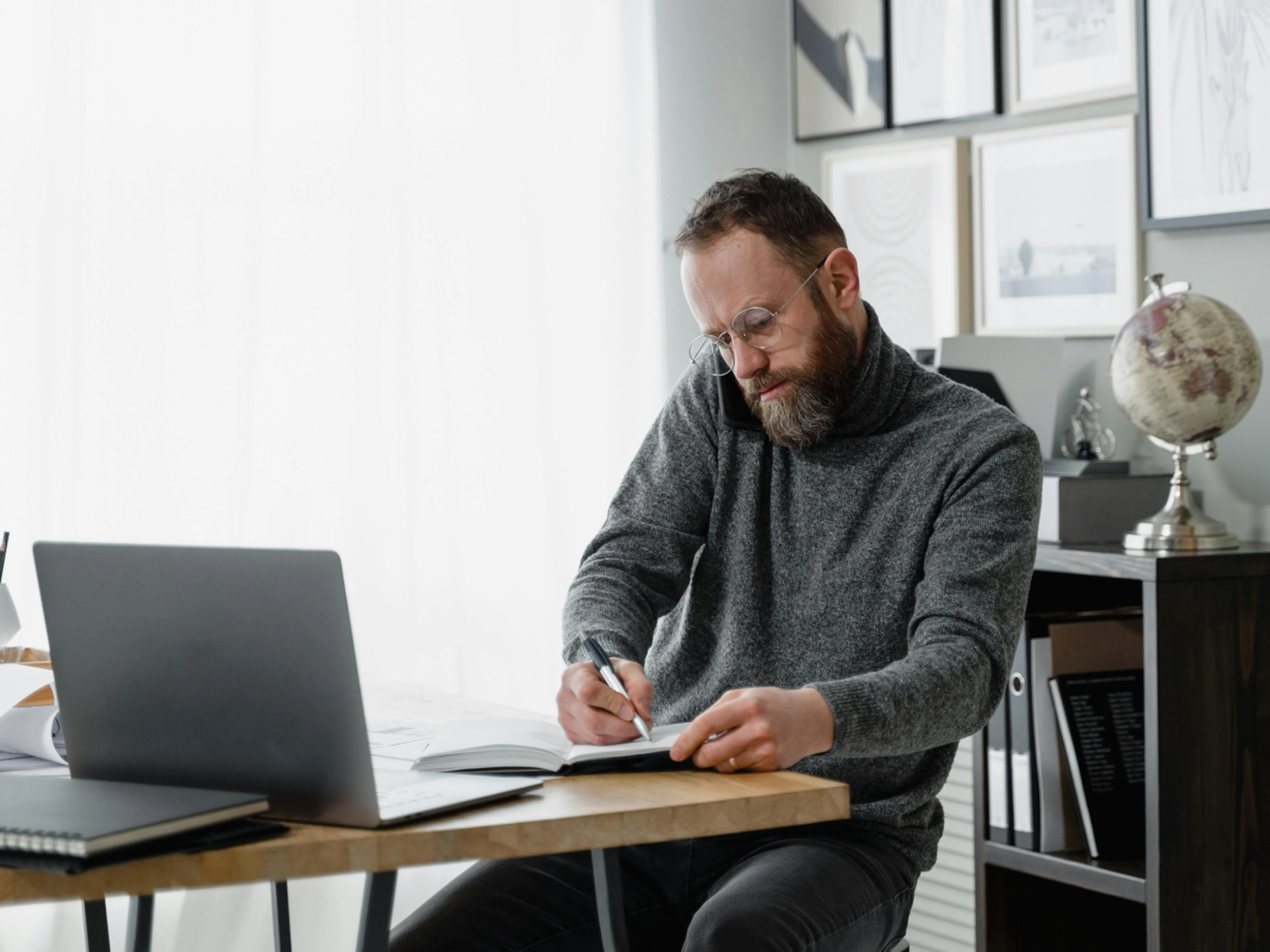 Man calling and writing down notes at his desk