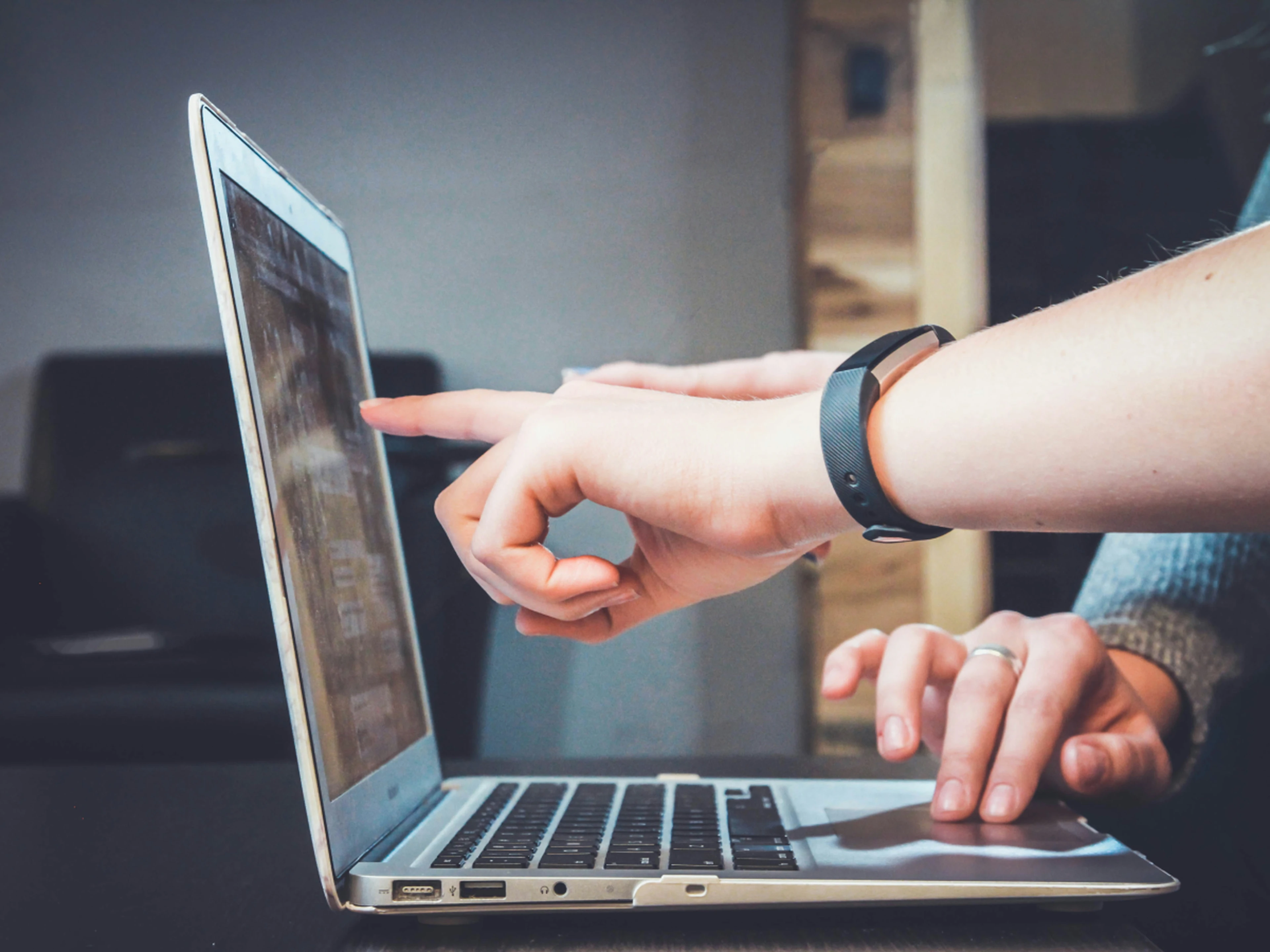 People pointing at data on a laptop screen