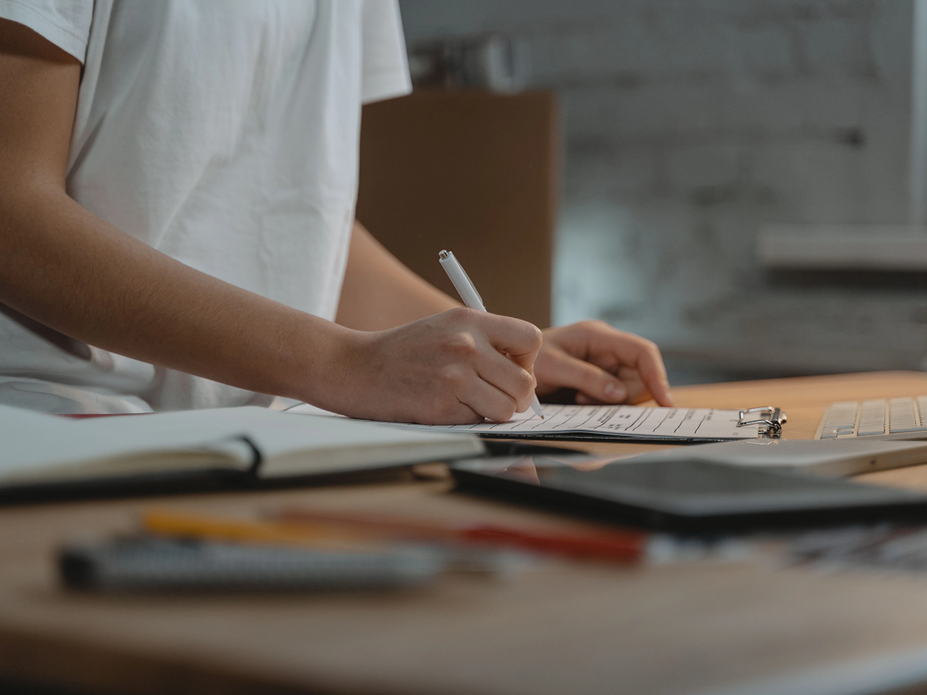 someone filling out a form on a cluttered desk