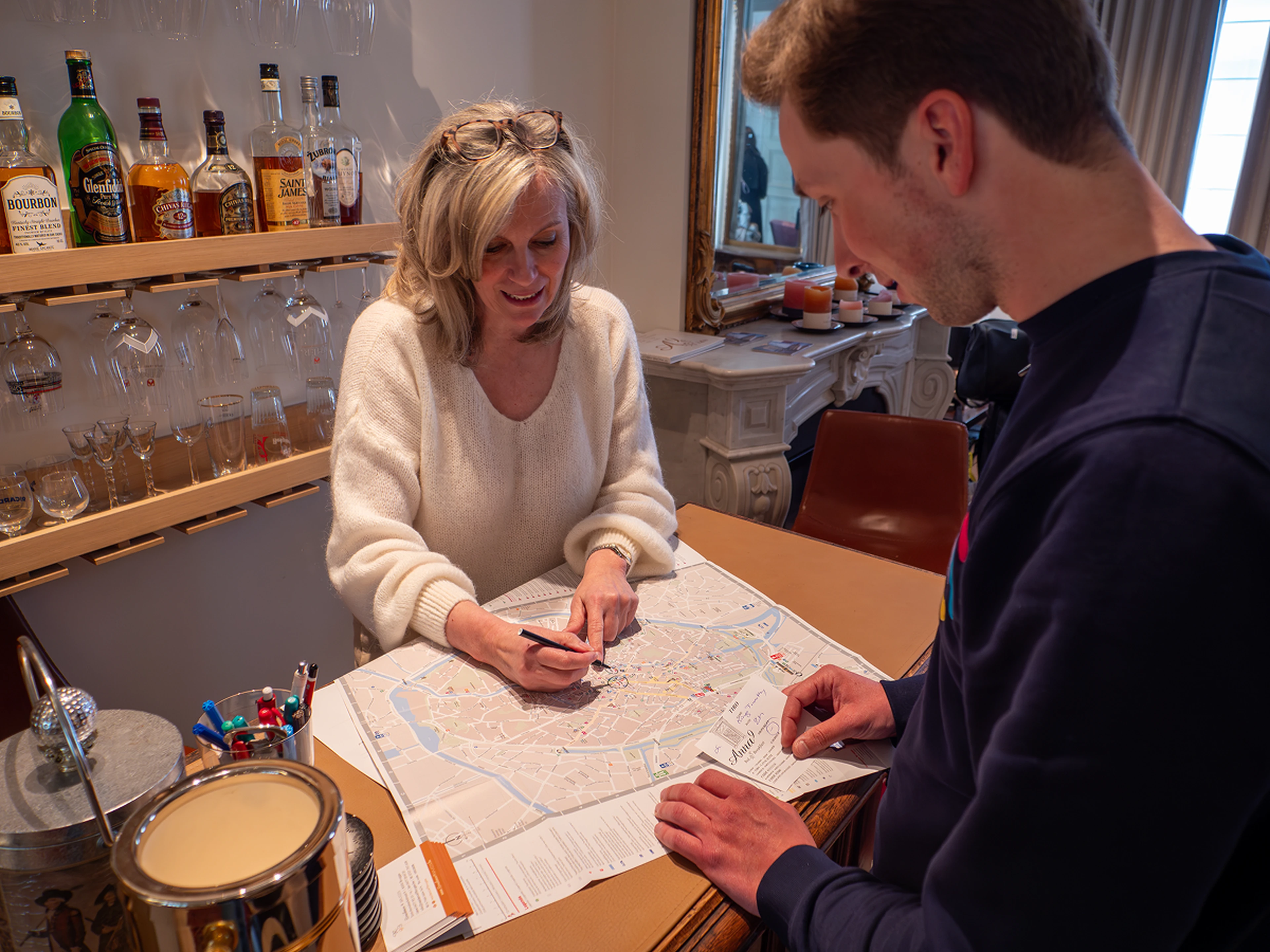 hotel employee smiling and giving a guest directions while pointing at a map