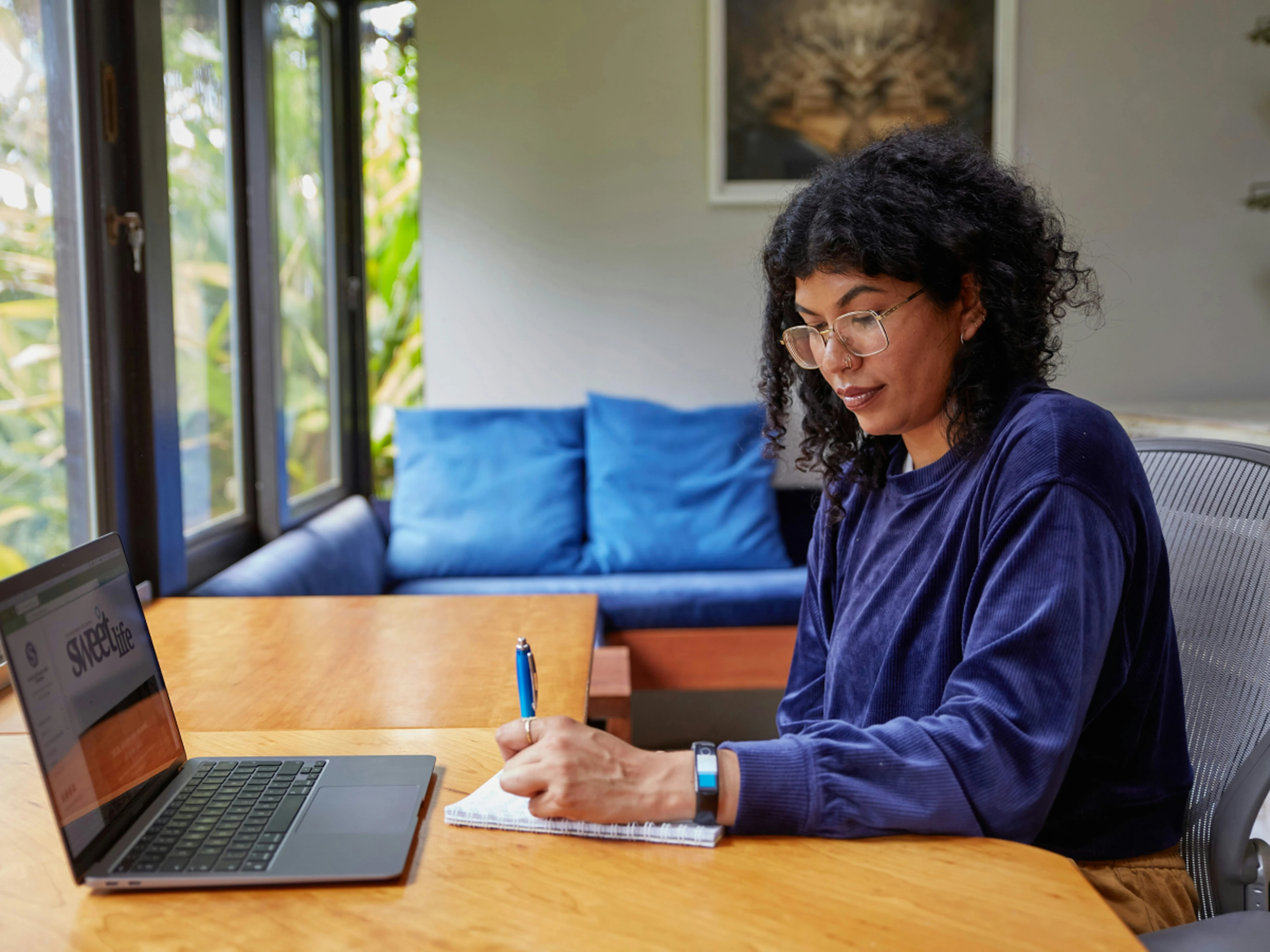 Woman writing a list with a laptop in front of her
