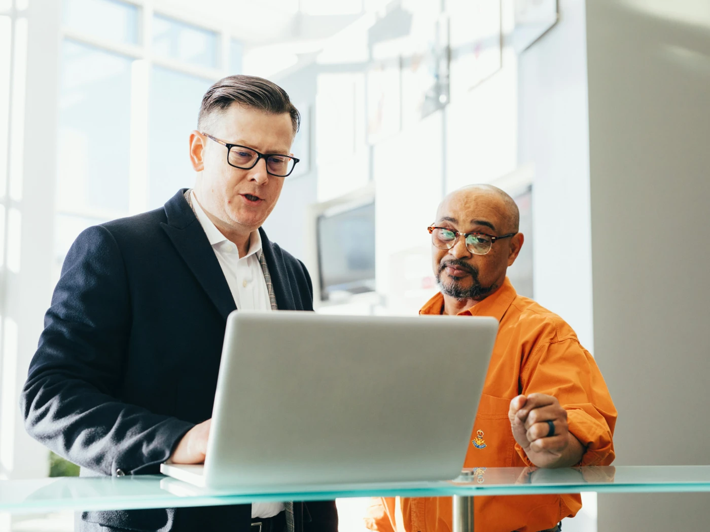 Two men discussing work and looking at laptop