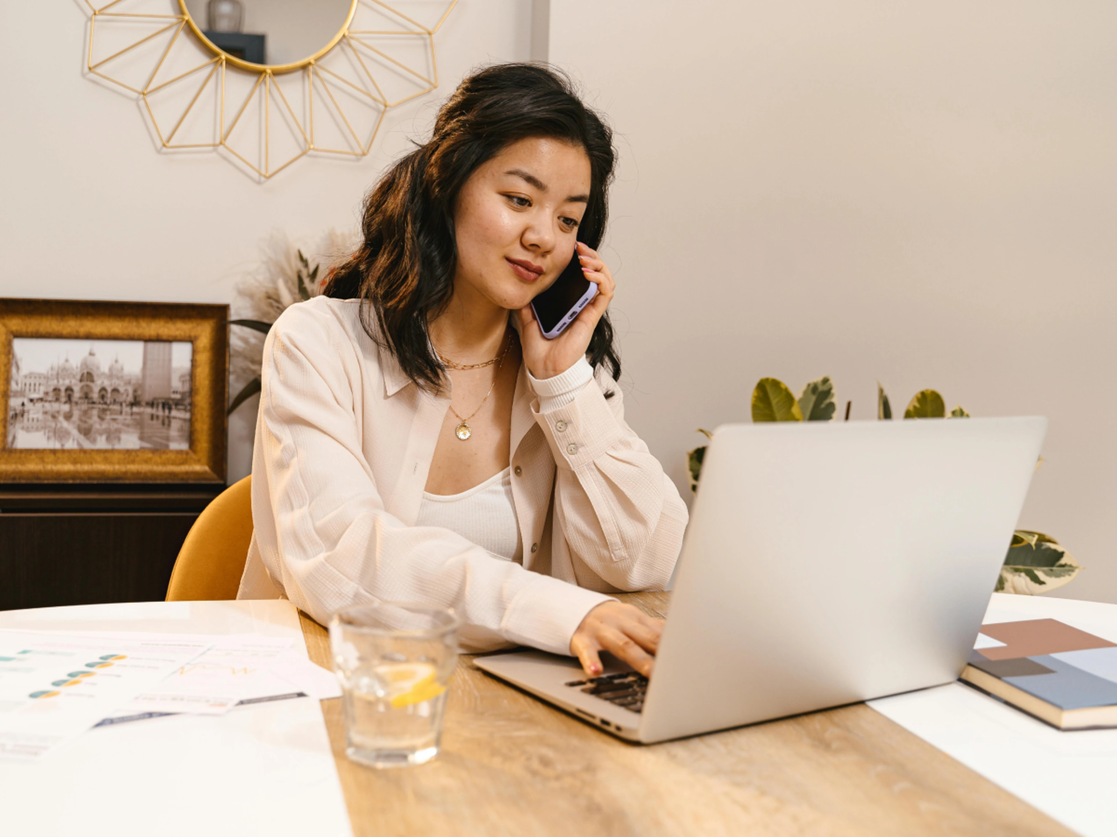 independent hotelier multitasking with a laptop and phone