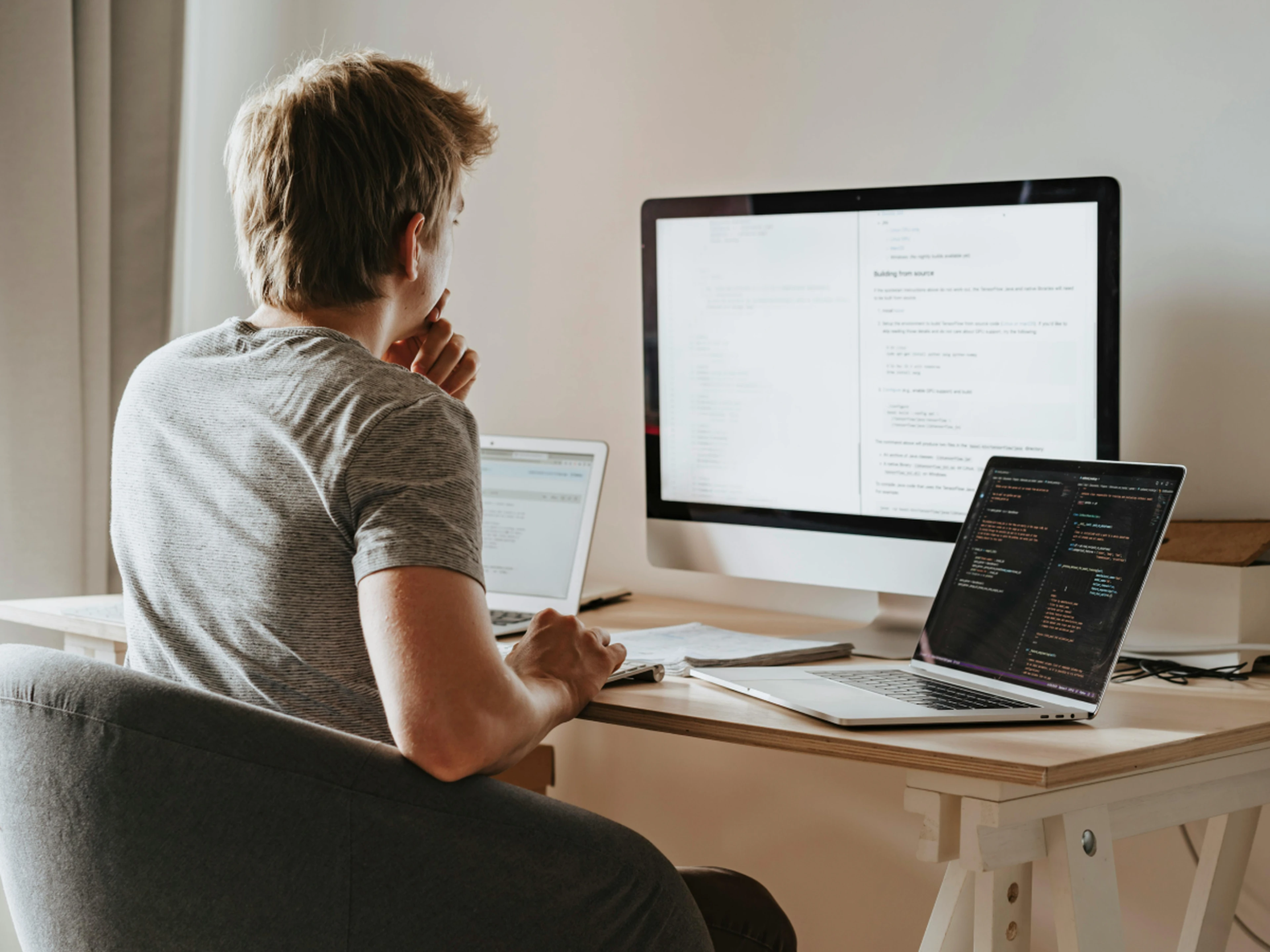 Man at desk looking at laptop and separate screen