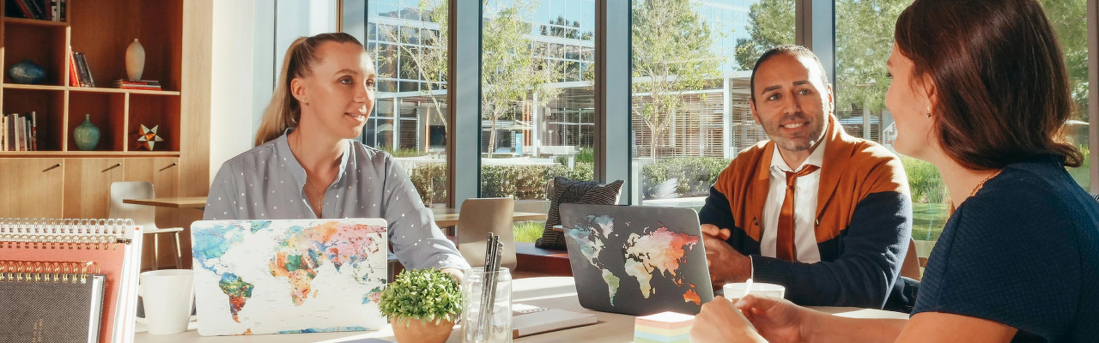 three hoteliers having a meeting with laptops featuring world map designs