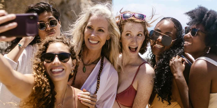 friend group on holiday taking a selfie at the beach