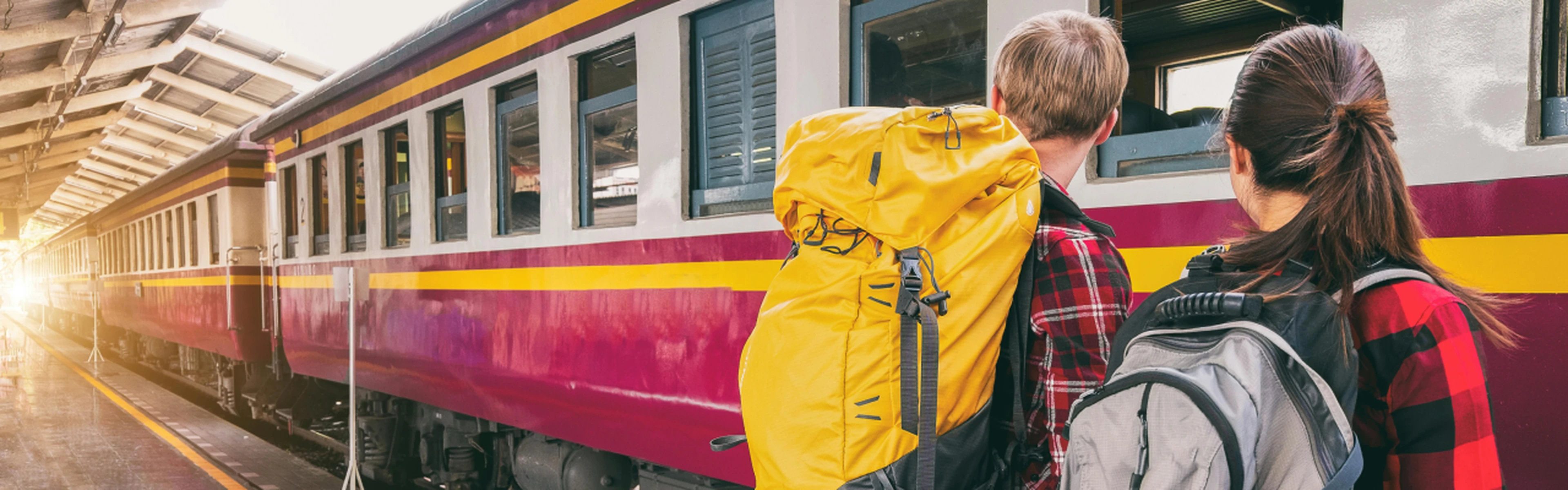 two travelers with backpacks ready to board their train
