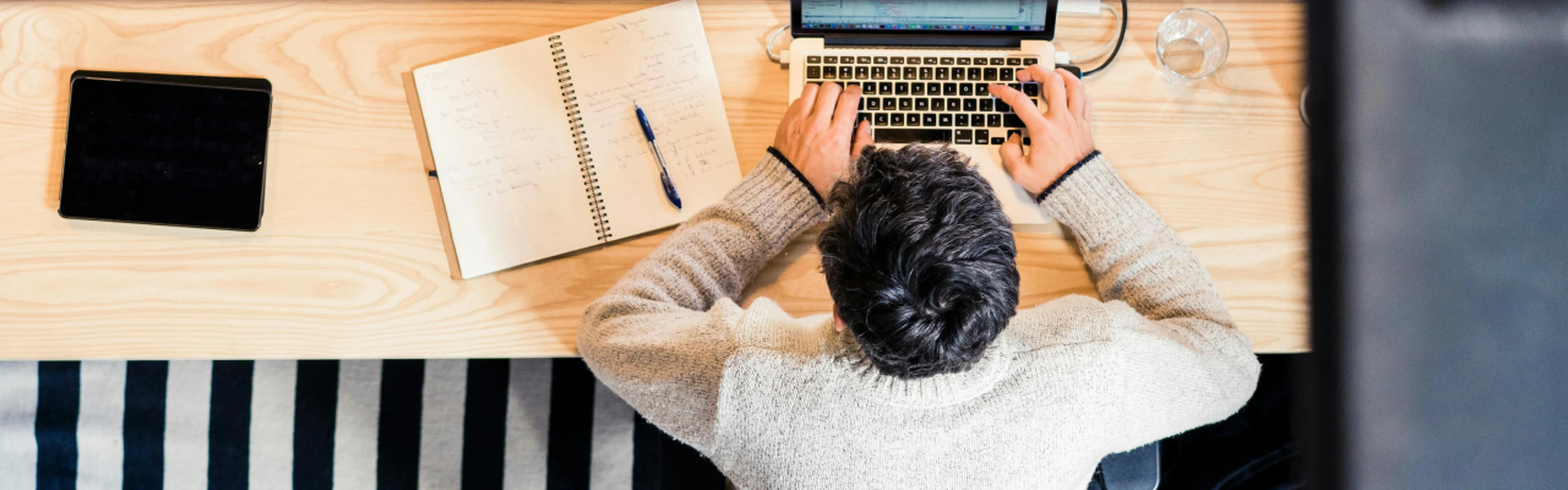 Man sitting at desk with laptop an notebook