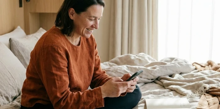 hotel guest in a hotel room reading an email on their smartphone
