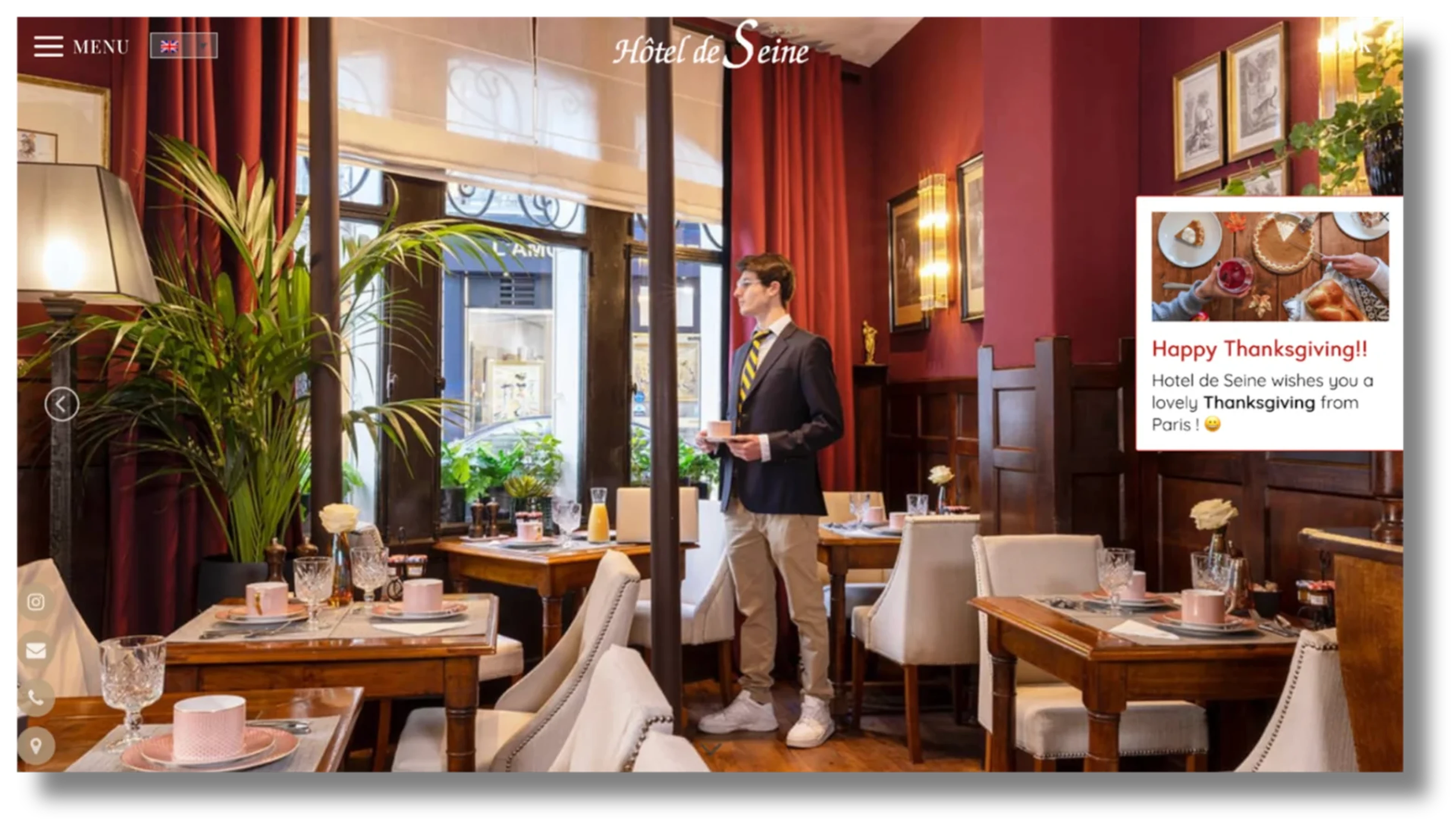 Elegant restaurant with a man in a suit standing near a table set for dining. A Thanksgiving greeting is displayed on the side.