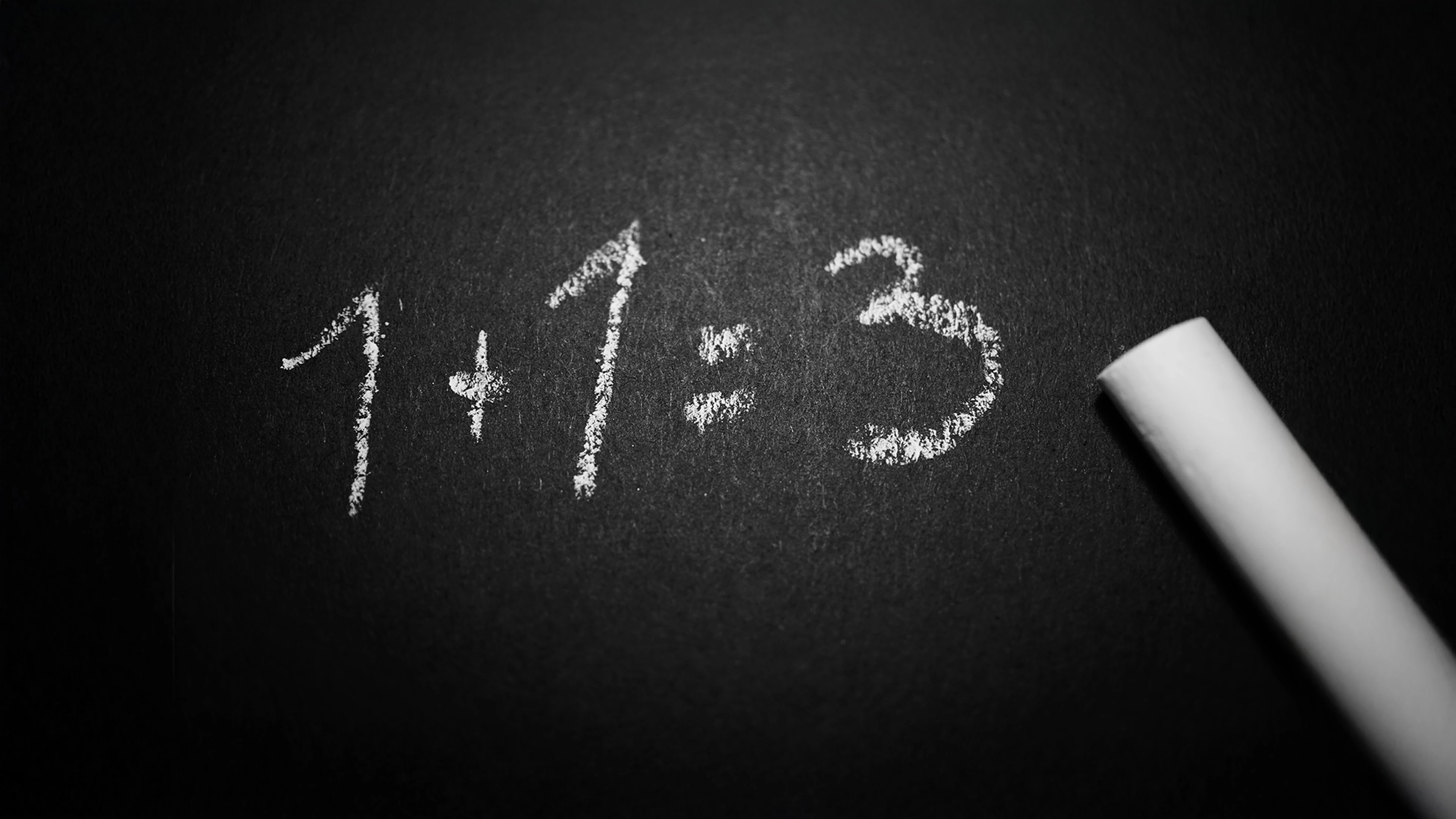 Chalkboard with the incorrect math equation "1 + 1 = 3" written on it