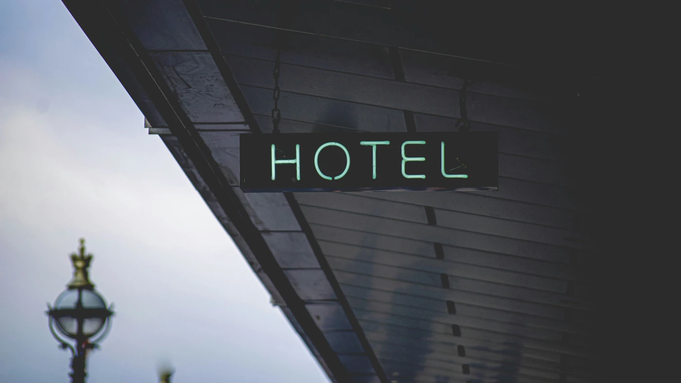 Neon "Hotel" sign hanging under a dark awning