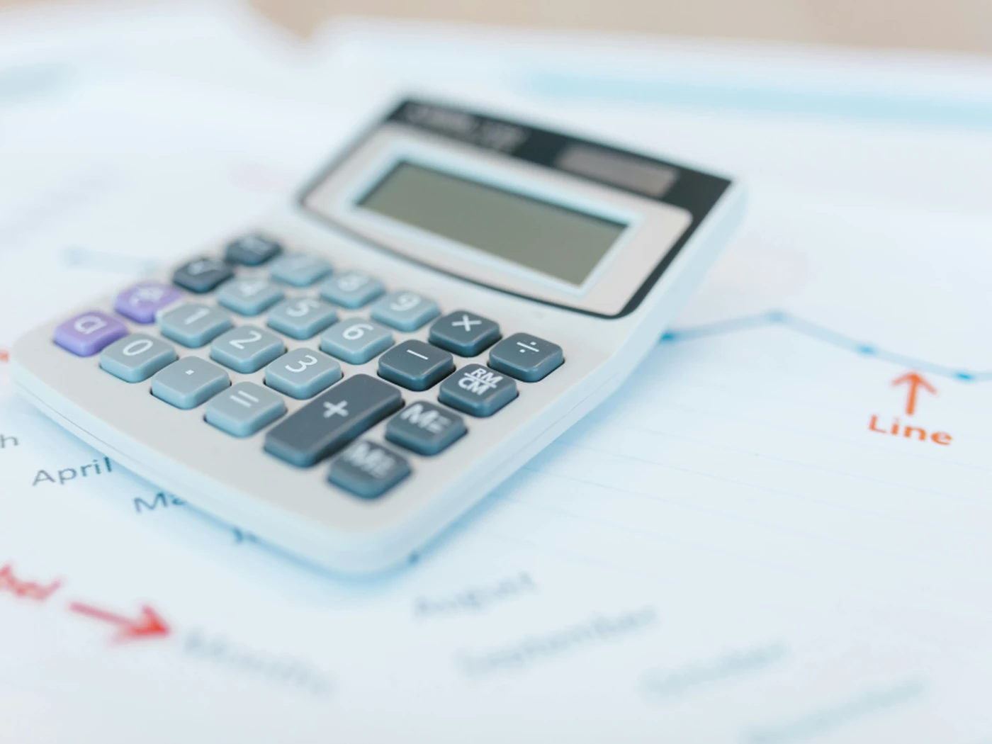 A calculator on a financial document with a line graph, showing months from April to October, and an arrow pointing to "Months."