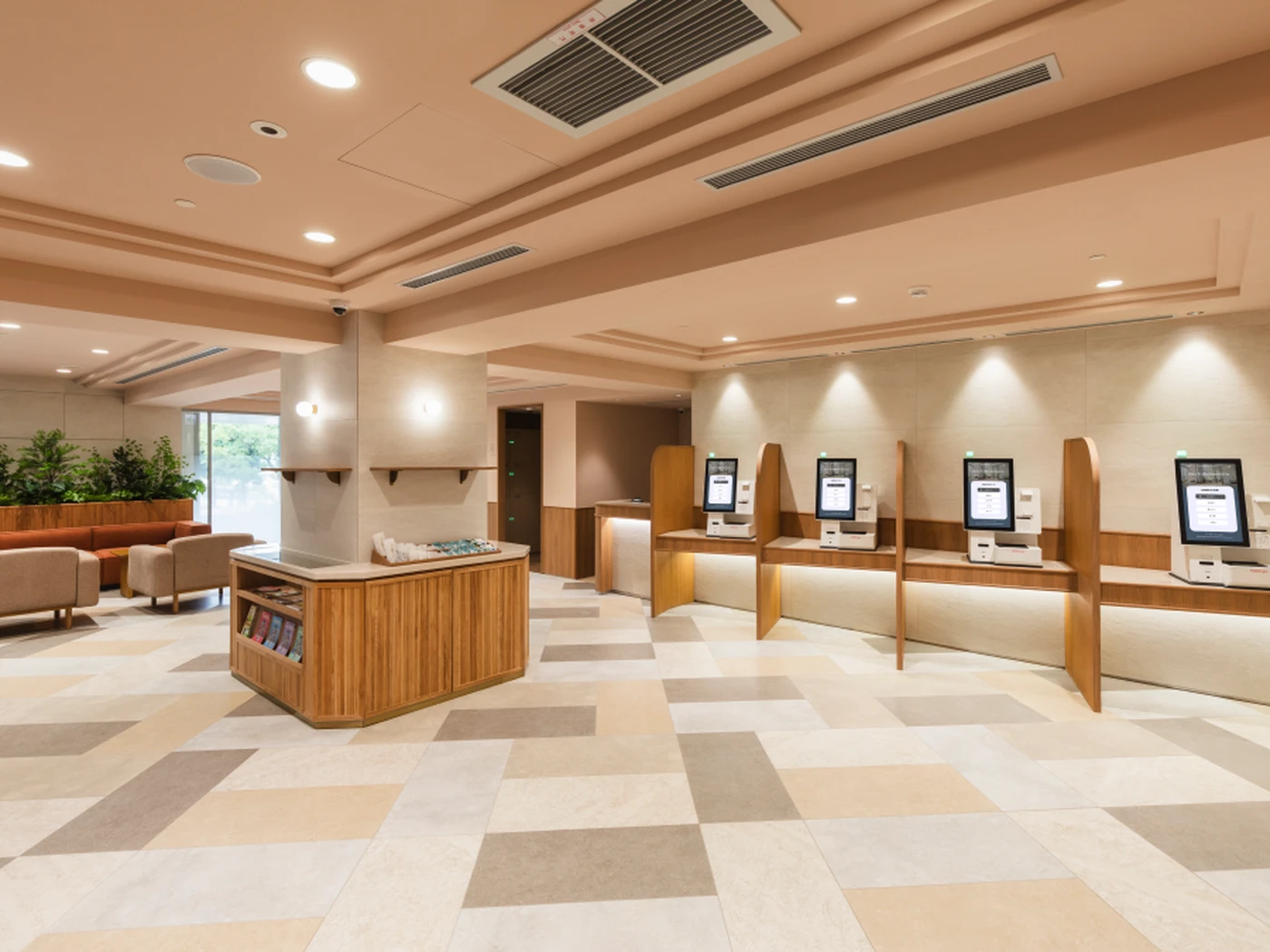 Bright, modern lobby with four self-service kiosks, lounge seating, wood finishes, plants, and a geometric tile floor.