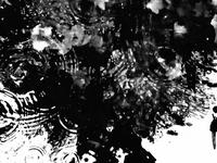 Abstract black and white droplets with swirling patterns and a small silhouette of a person on the right.