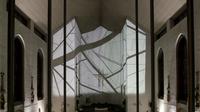 Interior of a church with abstract geometric projections on the wall, highlighting a crucifix at the center. Black lines on white background.