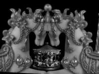 Black and white, ornate, symmetrical design with a central crown-like structure, featuring pearls and decorative chains on a black background.