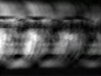Blurred grayscale image with overlapping faces and abstract textures, creating a sense of motion and depth.