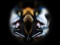 Abstract image with mirrored faces, dark background, and blurred features, creating a symmetrical, surreal effect.