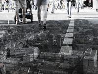 Aerial view of a cityscape blended with a street-level scene showing people walking on a sunny day.