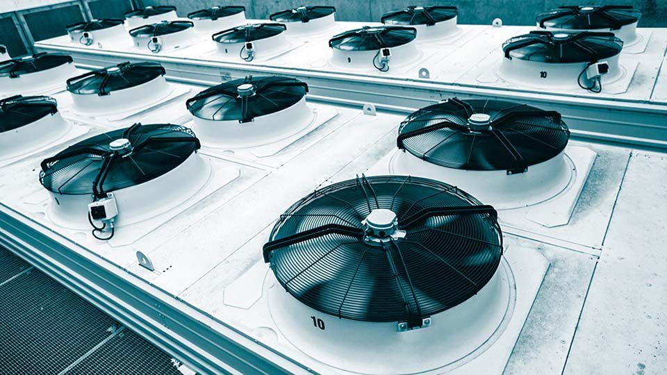 Rooftop HVAC system with rows of large industrial fans, featuring black blades and white bases, in an organized grid pattern.