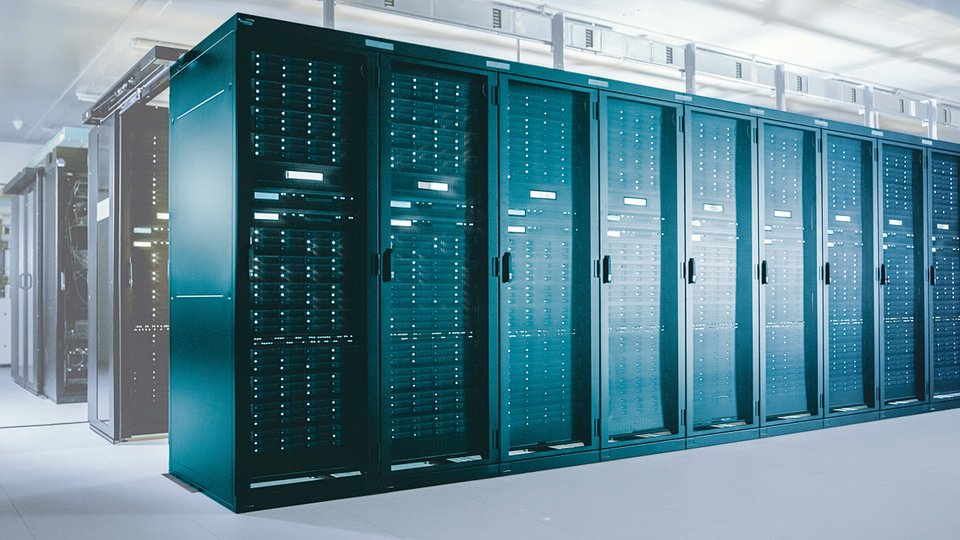 Rows of tall, dark server racks in a brightly lit data center, showcasing networking equipment and infrastructure.