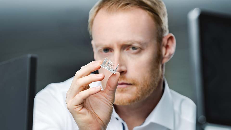 A man in a white shirt examines a power module closely, with a blurred background.