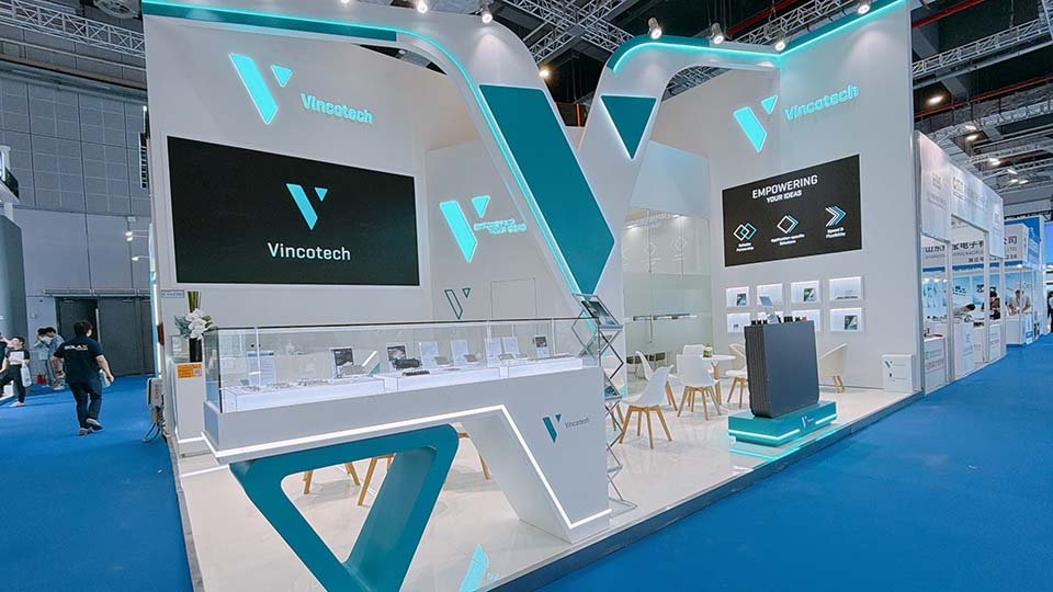Vincotech's booth at SNEC with digital screens, seating, and a sleek blue and white design on a blue carpeted floor.