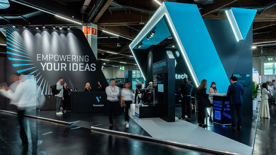 Vincotech's boot at PCIM with people interacting, featuring a bold design and the text "Empowering Your Ideas."