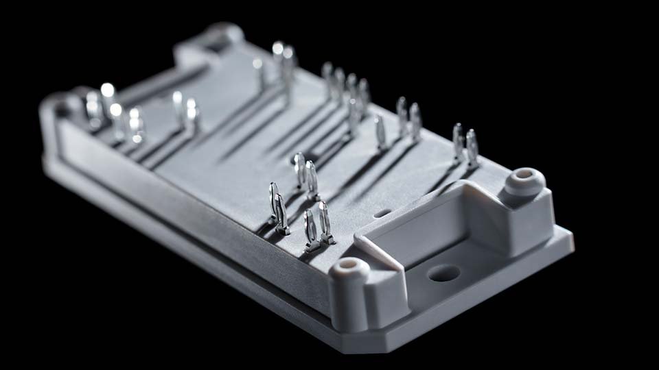 Close-up of a flowBOOST 1 with multiple press-fit pins on a black background, showing intricate details and shadows.