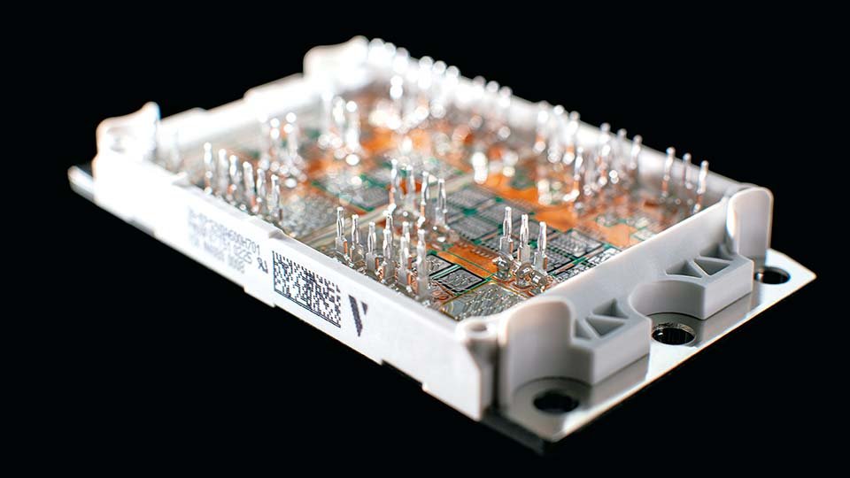 Close-up of a power module with multiple pins and intricate pathways, set against a black background.