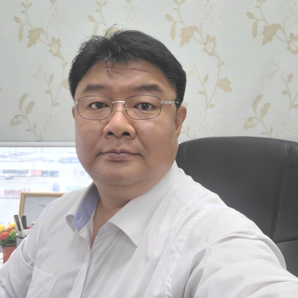 Sengyul Lee sitting in an office with floral wallpaper, looking directly at the camera.