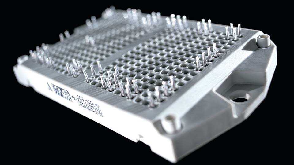 Close-up of a flow E3 housing with grid pattern and protruding pins, set against a black background.