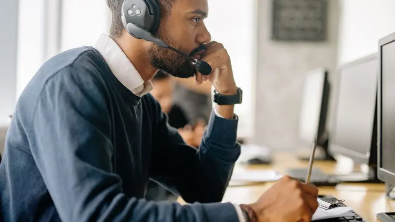 Customer support agent wearing a headset at a computer