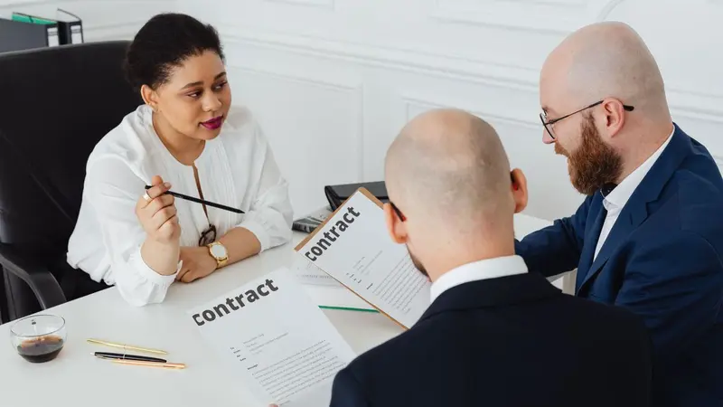 Three people discussing a contract at a table