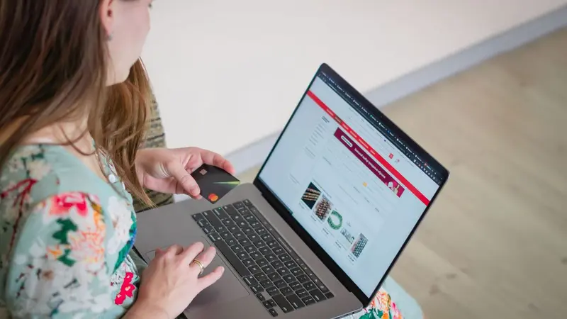 Woman sitting on the floor using a laptop with an online store page open