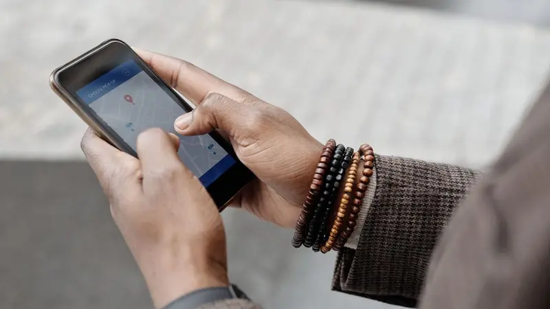 Hands holding a smartphone while standing outdoors