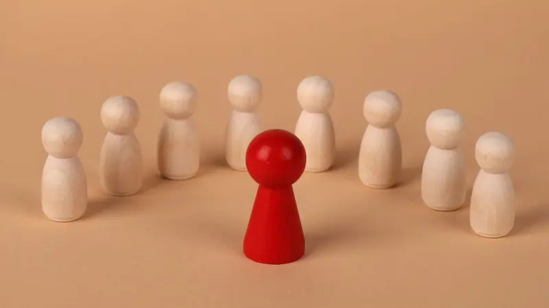 Row of wooden figures with one red figure standing out