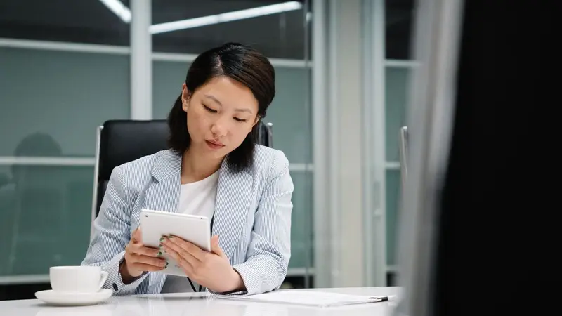 Woman sitting at a desk reading a tablet