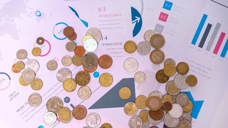 Coins spread over printed charts, representing budget allocation