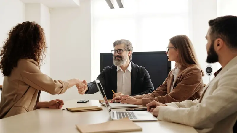 Four colleagues meeting around a table with laptops