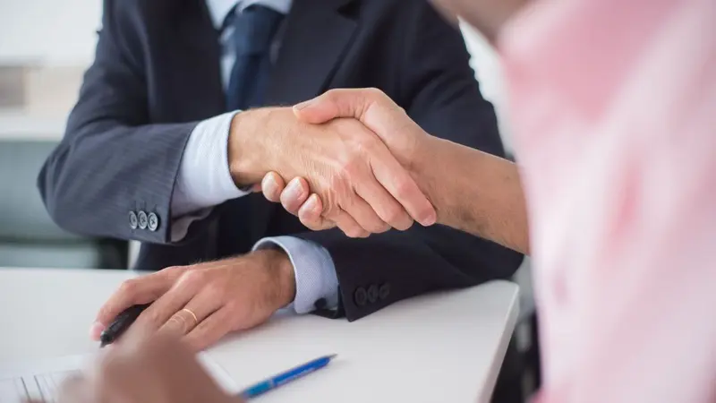Two business people shaking hands over a desk