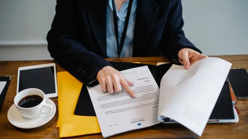 Manager reviewing paper documents at a desk with a coffee