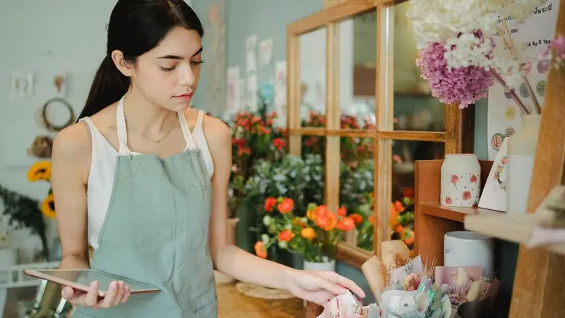 Woman florist holding a tablet in a small shop