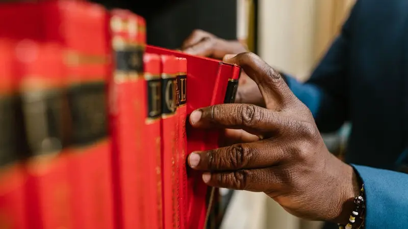 Hand pulling a red book from a shelf