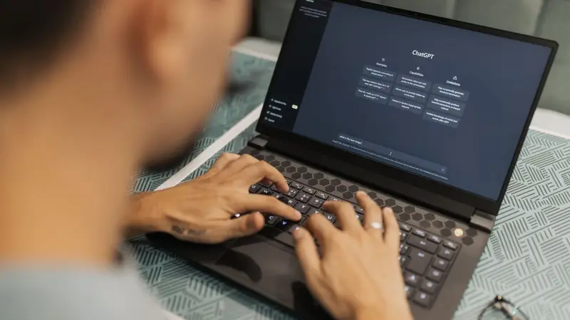 Person typing prompts on a laptop with a dark interface